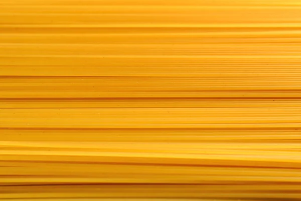 Fundo de espaguete deitado horizontalmente. macarrão amarelo como costas — Fotografia de Stock