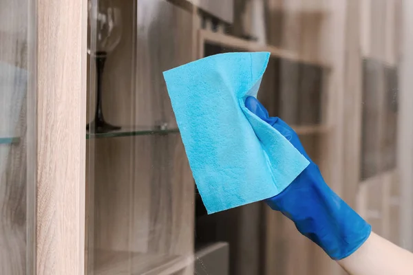 girl in blue gloves cleans the glass with a blue rag