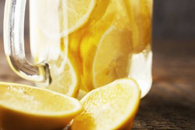 ev kontrast aydınlatma ahşap bir arka planda limonata yaptı. Su ile dolu bir kavanozda limon dilimleri