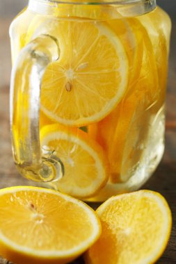 ev kontrast aydınlatma ahşap bir arka planda limonata yaptı. Su ile dolu bir kavanozda limon dilimleri