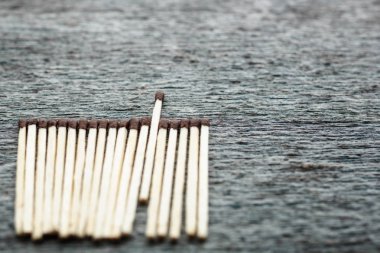 Satır eşleşme gri bir ahşap zemin üzerine. Bir maç öne çıkmaktadır. Lider kavramı. Kopya alanı ile fotoğraf