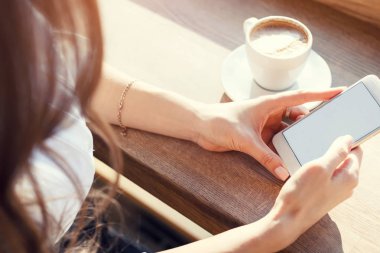 kafede genç kadın cep telefonu kullanır ve kahve içiyor