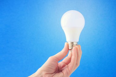 LED Lamba mavi bir arka plan üzerinde elinde. Fikir kavramı