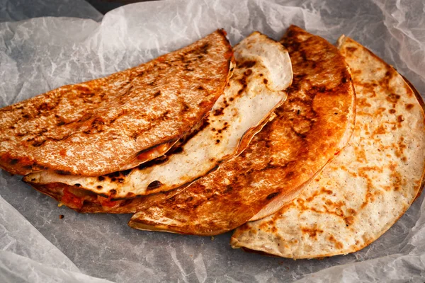 Home cooked Mexican quesadilla is stacked on a parchment.