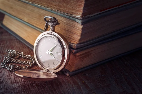 Вінтажний кишеньковий годинник на ланцюжку і старі книги на дерев'яному фоні — стокове фото