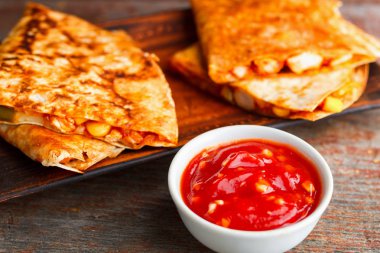 iki adet quesadilla bir plaka ve bir ahşap üzerine salsa sos