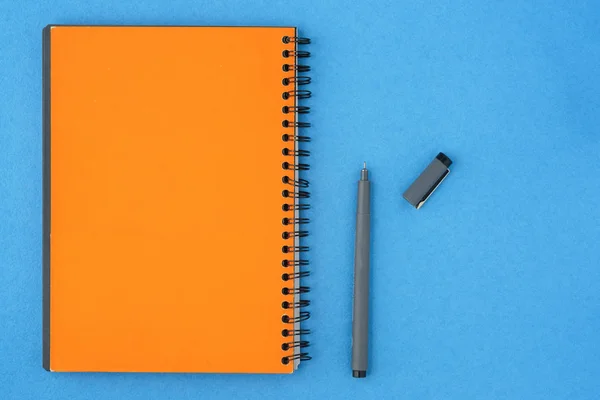 Cuaderno vacío amarillo y pluma con una tapa abierta en un backgro azul — Foto de Stock