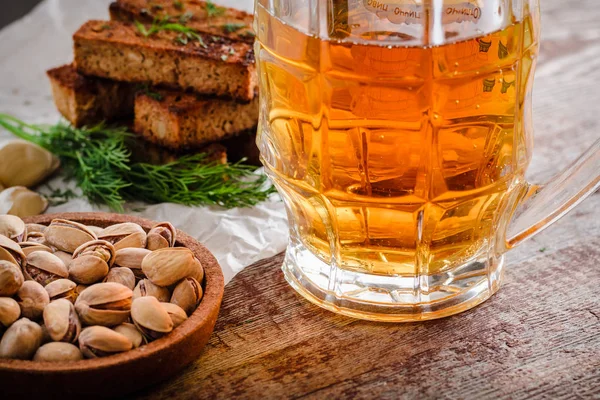 Кружка светлого пива и закуски на деревянном столе — стоковое фото