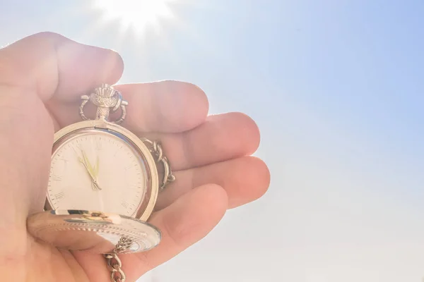 Кишеньковий годинник в руці і блакитне небо на сонці . — стокове фото