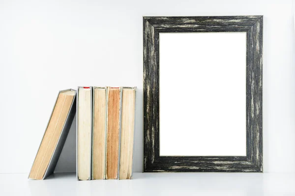 Marco negro vacío y libros antiguos sobre un fondo blanco . — Foto de Stock