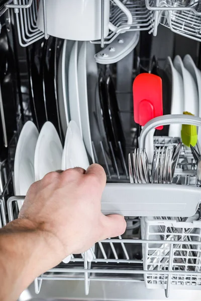 Чоловік вивантажує чистий посуд з посудомийної машини — стокове фото