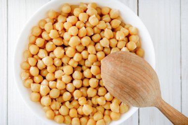 Bir kase ve bir tahta kaşık beyaz bir tablo üzerinde pişmiş nohut