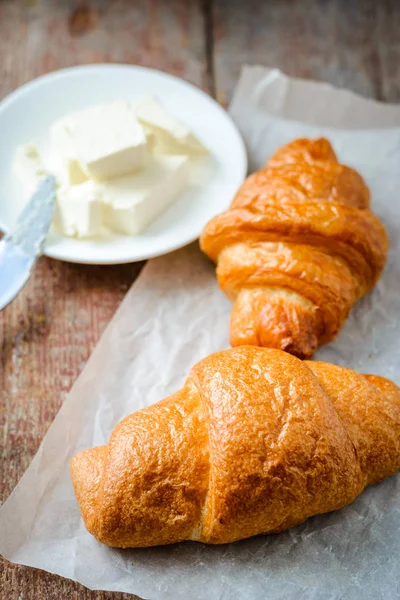 two appetizing croissants with butter on a wooden table