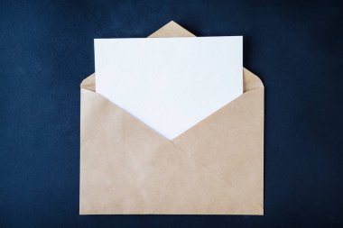 Koyu arka plan üzerinde kahverengi enveloop boş beyaz kart