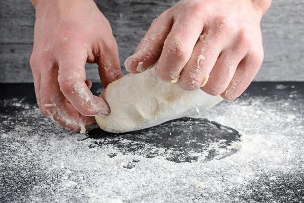 Руки замішують тісто на дерев'яному столі — стокове фото