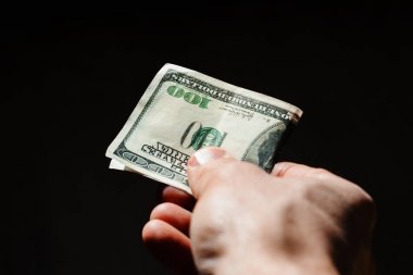 Karanlık bir arka plan üzerinde elinde Amerikan Doları