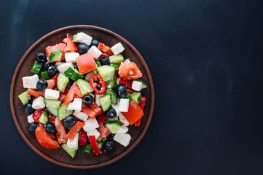 Karanlık bir arka plan üzerine bir tabak içinde Yunan salatası