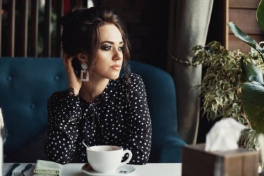 Kafedeki ya da restorandaki kadın pencereye bakar.