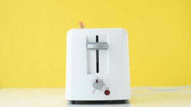 Eller tost makinesini sarı arka planda beyaz tost makinesine koyar ve tost makinesini açar. Mutfak aletleriyle kahvaltı hazırlıyorum.