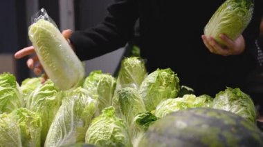 Kadın markette Çin lahanasını seçiyor. Kız süpermarketten sebze alır. Alışveriş konsepti