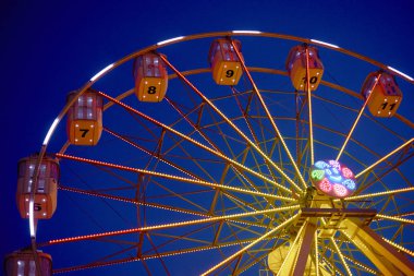 Bir gece şehrindeki lunaparkta yanan dönme dolap.