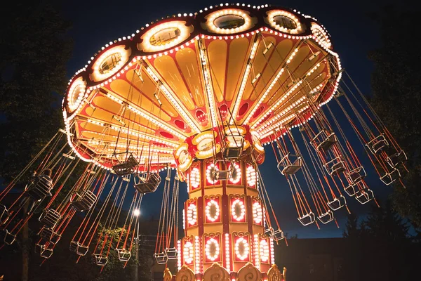 Carrossel de corrente oscilante iluminado no parque de diversões à noite — Fotografia de Stock