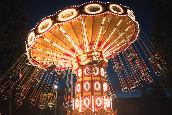 Illuminated swing chain carousel in amusement park at the night