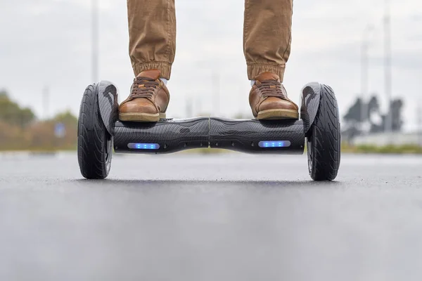 Close-up van de mens met behulp van hoverboard op asfalt weg. Voeten op elektrisch — Stockfoto