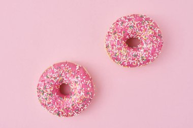 Pembe arka planda iki donut serpiştirilmiş.