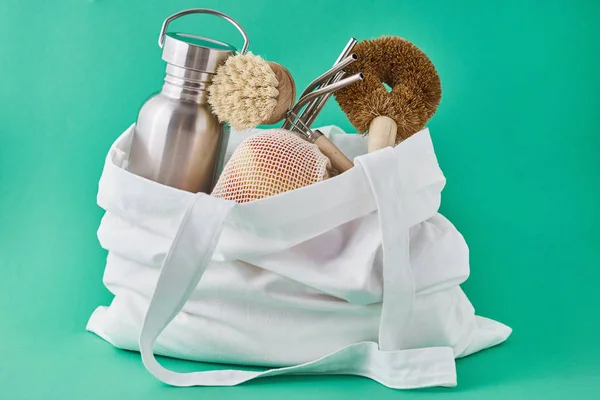 Zero waste concept. Reusable eco friendly items in a shoppping bag on green background — Stock Photo, Image