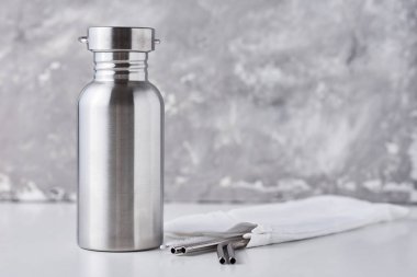 Alüminyum şişe ve metal tüpleri gri bir sırt deliğinde pamuk torbanın içinde.