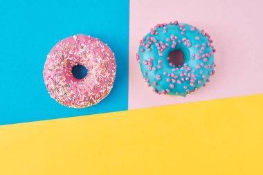 Pastel pembe, sarı ve mavi arkaplanlı çörekler. Minimalizm yaratıcı yemek kompozisyonu. Düzleştirme biçimi