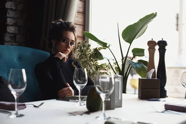 Vrouw zit aan tafel in café of restaurant en drinkt een koffie — Stockfoto