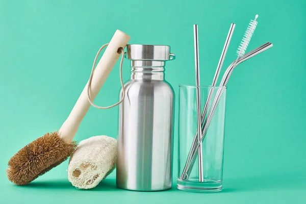 Zero waste concept. Eco friendly reusable items aluminun bottle and metal tubes in glass on a green background — Stock Photo, Image