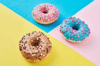 Pastel pembe, sarı ve mavi arkaplanlı çörekler. Minimalizm yaratıcı yemek kompozisyonu. Düzleştirme biçimi