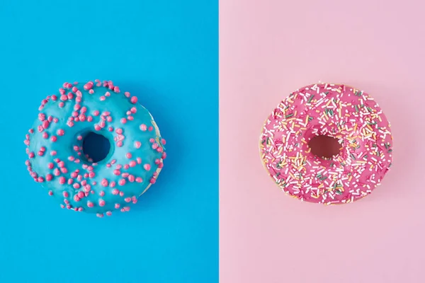 Két fánk pasztell rózsaszín és kék háttérrel. Minimalizmus kreatív ételek összetétele. Lapos fektetési stílus — Stock Fotó