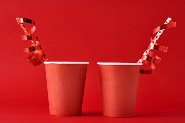 Dos tazas de café de papel con decoraciones y paja en el fondo rojo. Concepto festivo de San Valentín — Foto de Stock