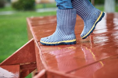 Yağmurlu bir günde mavi lastik çizmeli çocuk ıslak kaygan merdivenlerden aşağı iniyor. Çocuk güvenliği kavramı