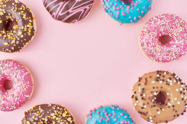 Rengarenk donörlerin çerçevesi dekore edilmiş süslemeler ve pastel pembe arka planda krema, üstten düz görünüm