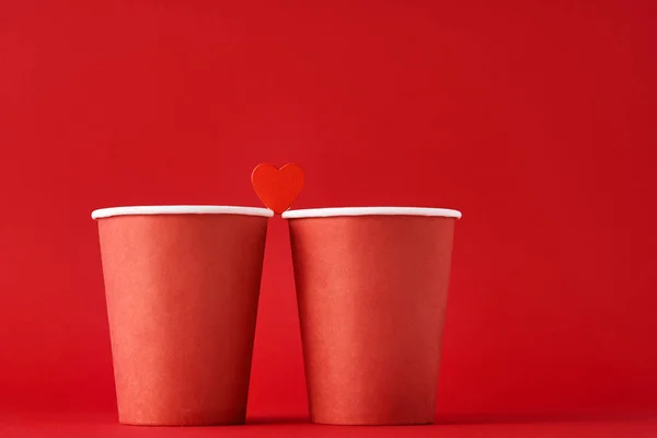 Two red coffee cups with  heart as couple in love on the red background. Valentines day and romantic concept