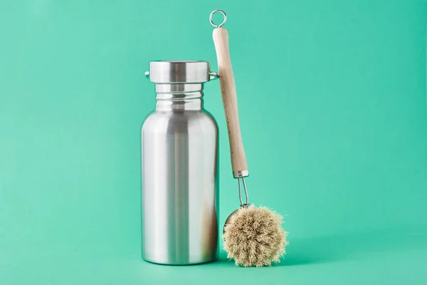 Zero waste concept. Eco friendly reusable aluminun bottle and wooden cleaning brush on a green background — Stock Photo, Image