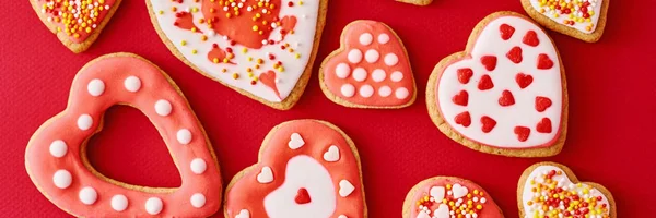 Fundo de decorado com gelo e biscoitos de forma de coração envidraçado no fundo vermelho, bandeira longa. Conceito de comida Dia dos Namorados — Fotografia de Stock
