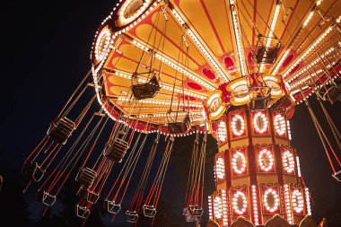 Illuminated swing chain carousel in amusement park at the night clipart