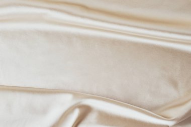 Kıvrımlı altın renkli ipek arka plan. Dalgalanan saten yüzeyin soyut dokusu