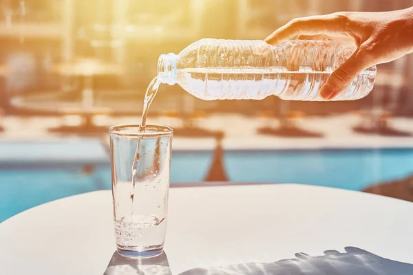 Vrouw hand gieten water in glas uit plastic fles — Stockfoto