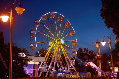 Bir gece şehrindeki lunaparkta yanan dönme dolap.