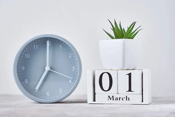 带有木制日历日期的闹钟，3月1日，放置在桌上 — 图库照片