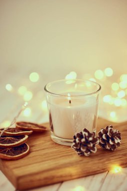 Süslü, yanan beyaz mum ve tahta bir masanın üzerindeki Bokeh 'te çelenk ışıkları. Konforlu ev ve hygge konsepti