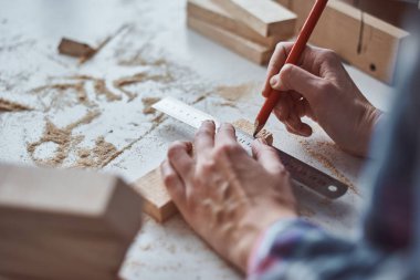 Marangoz elleri tahta bir kalemle ölçü alıyor. Diy ahşap işçiliği ve mobilya yapımı kavramı