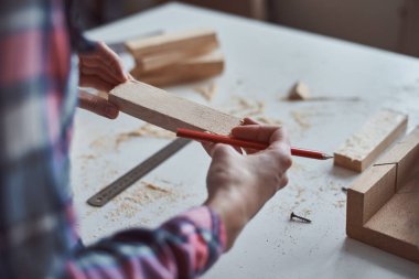 Marangoz elleri tahta bir kalemle ölçü alıyor. Diy ahşap işçiliği ve mobilya yapımı kavramı